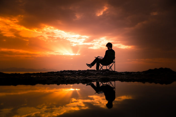 Man reading by a lake at sunset